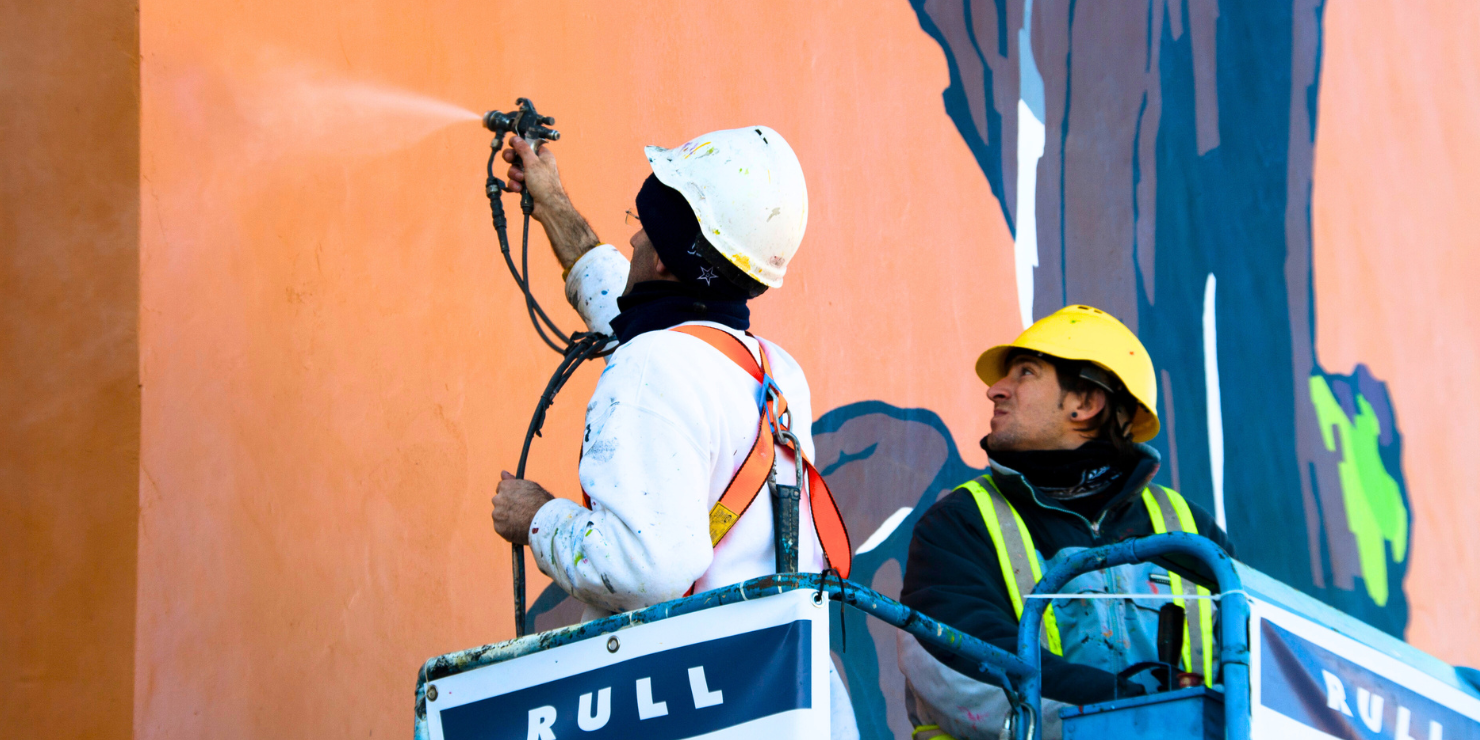 dos trabajadores de rull services haciendo el mantenimiento profesional de pintura en la fachada exterior de un edificio