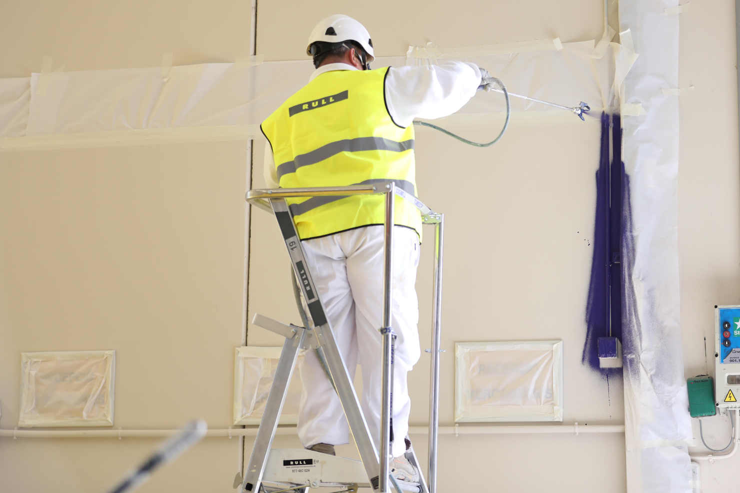 Profesional de rull services aplicando pintura en nave industrial